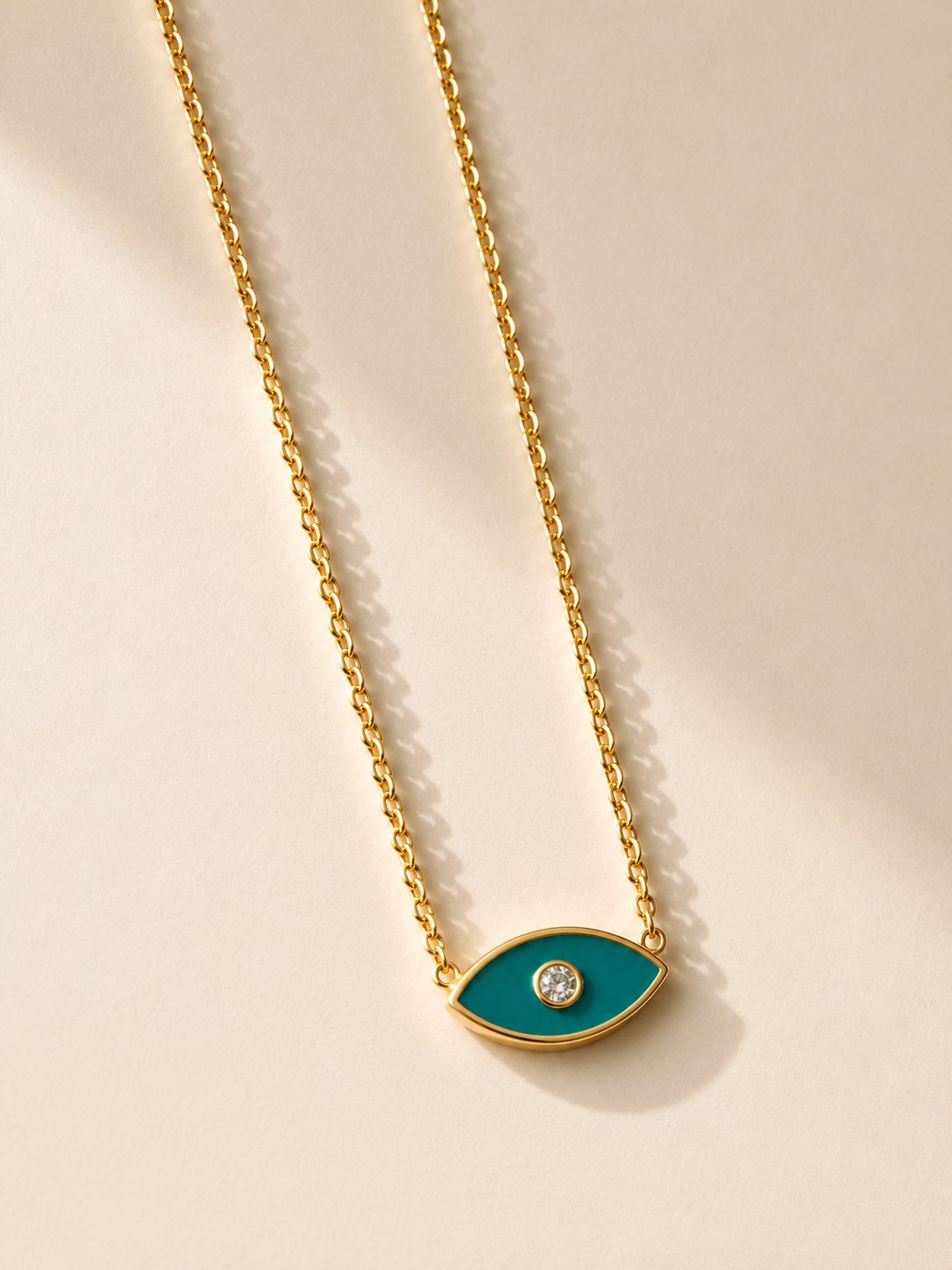 0cad7e00-b25d-4d03-afd3-27785da6bfa3 Colar em aço dourado com pendente de olho turco verde, contorno dourado e pedra brilhante central