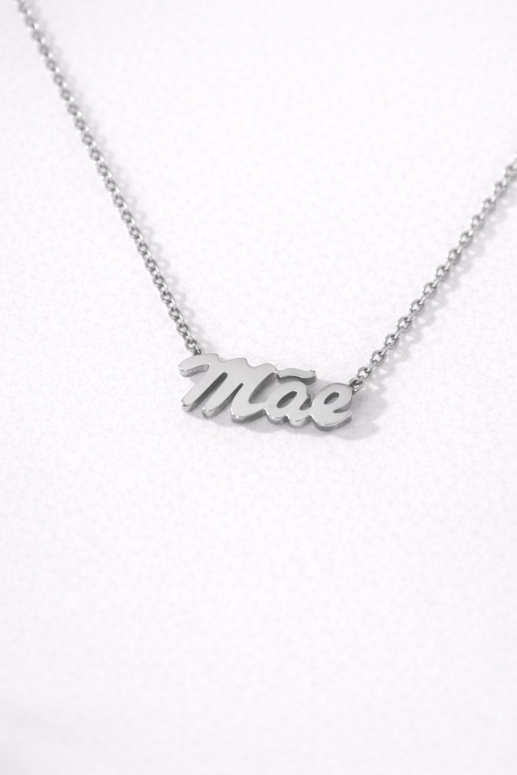 0f9e7ac1-5520-4c28-93b5-929f3311ac20-1 Colar em aço com pendente em forma da palavra Mãe e corrente delicada