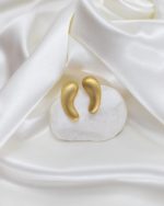 Brincos dourados em forma de gota sobre tecido branco