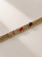Pulseira em aço dourado com várias correntes e três detalhes coloridos em tons de rosa, vermelho e roxo