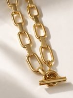 Colar em aço dourado com elos retangulares alongados e fecho frontal em T
