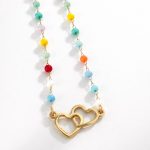 Colar em aço dourado com contas coloridas e pendente de dois corações entrelaçados