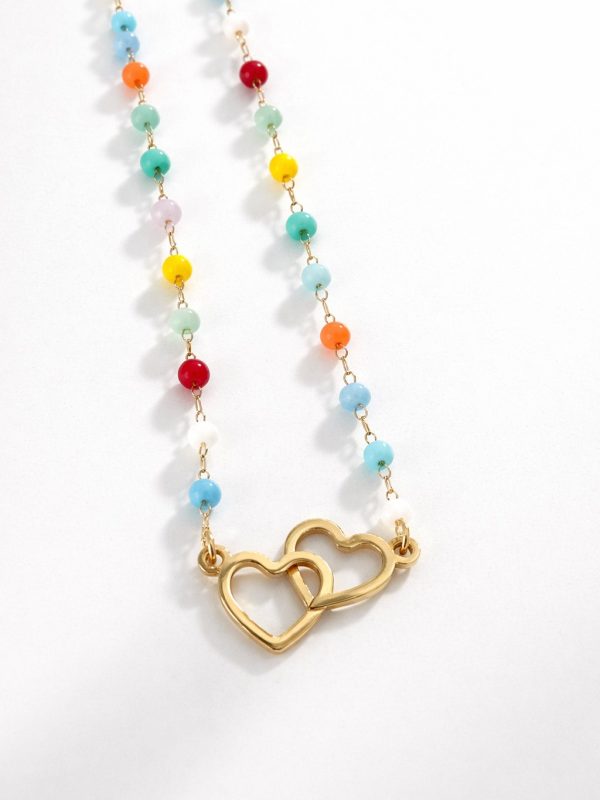 Colar em aço dourado com contas coloridas e pendente de dois corações entrelaçados